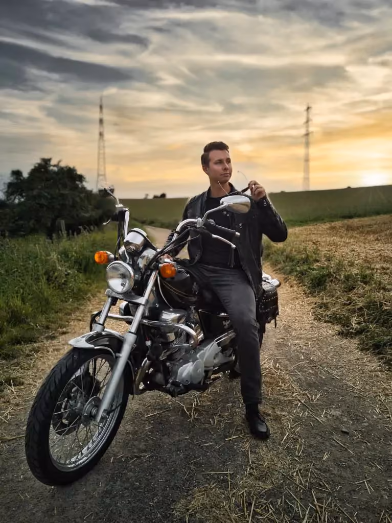 Peter Krück sitting on a motorbike on a country road at sunset